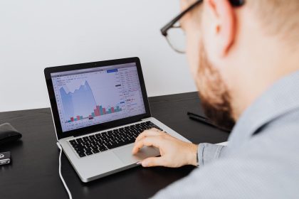 Profissional analisando dados empresariais e gráficos financeiros em um laptop, em ambiente interno.