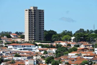 Vista de área residencial de Itapira, no interior de São Paulo, com casas e um edifício alto sob céu azul.