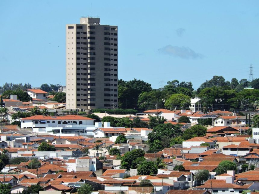 Vista de área residencial de Itapira, no interior de São Paulo, com casas e um edifício alto sob céu azul.