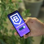 Mão segurando um smartphone com um aplicativo de blockchain exibido na tela.