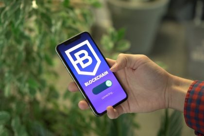 Mão segurando um smartphone com um aplicativo de blockchain exibido na tela.